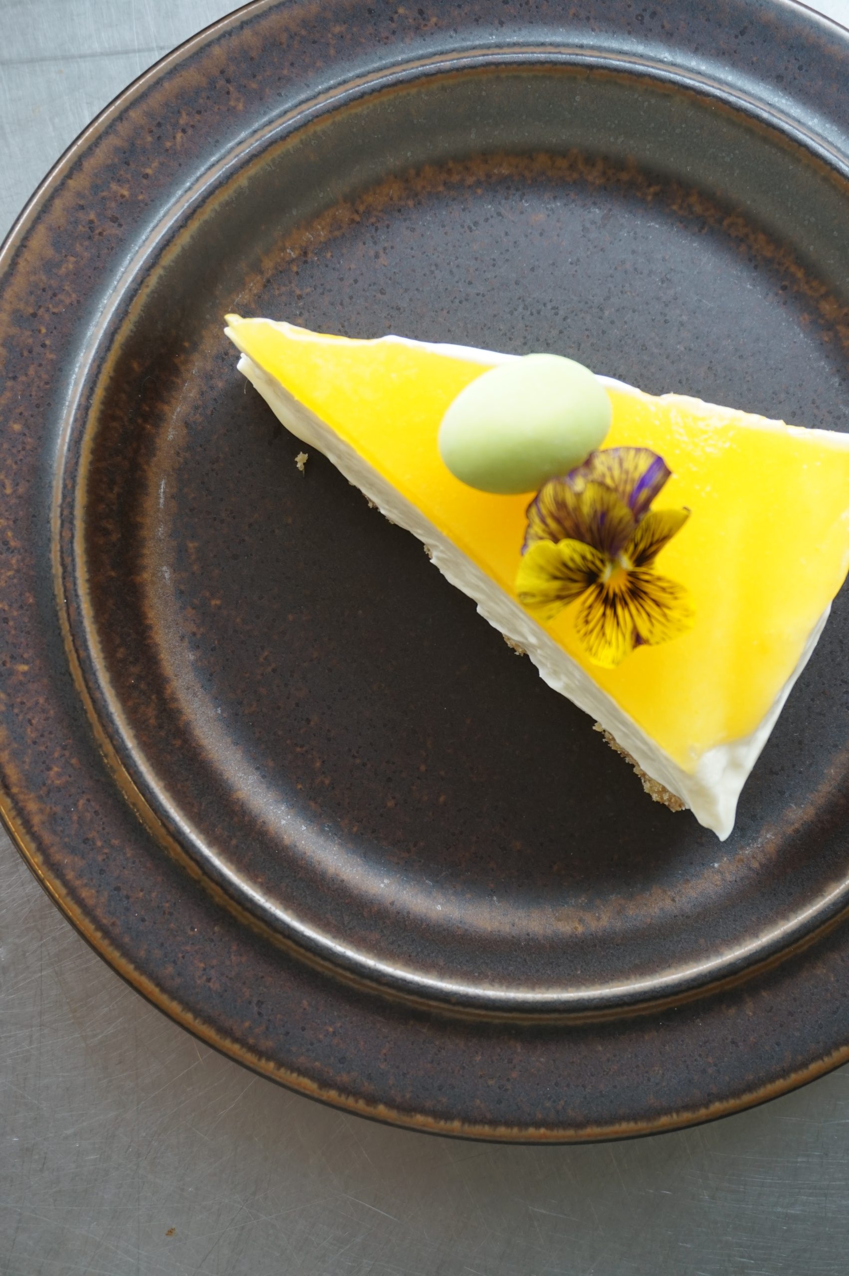 Yellow cake slice on dark plate